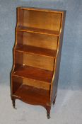 A reproduction mahogany narrow waterfall bookcase supported on turned legs ending in castors.50 cm
