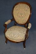 A Victorian armchair with padded back and seat supported on cabriole legs and ending in porcelain