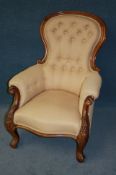 A Victorian mahogany button back armchair with curving arms and serpentine fronted seats supported
