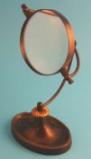 An early 20th century desk top magnifying glass on stand with pen tray.30 cm high19 cm wide