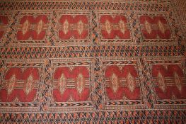 A Bokhara rug having two rows of square shaped medallions containing lozenge motifs, within