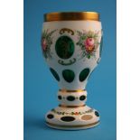 A Bohemian glass goblet on a green ground overlaid with white opaque glass and decorated with enamel