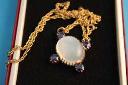 A 9ct gold pendant set with a central cabochon moonstone with four sapphires on a 9ct gold chain.