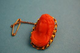 An orange coral cameo brooch.