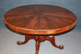 A Victorian mahogany circular tilt top dining table with segmented top, supported on a turned