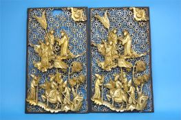 A pair of Chinese pierced fretwork panels each decorated with figures and horses in relief behind an
