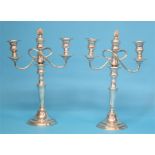 A pair of silver plated two branch candelabra with three sconces, supported on tuned columns and