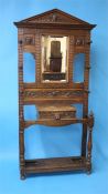 A heavily carved oak hallstand with central mirror below a single drawer with lion mask handle,