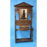 A heavily carved oak hallstand with central mirror below a single drawer with lion mask handle,