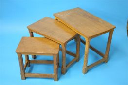 A Robert "Mouseman" Thompson oak nest of three rectangular tables with octagonal legs and a carved
