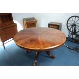 A Victorian mahogany circular tilt top dining table with segmented top, supported on a turned