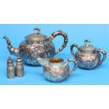 A Chinese silver tea set decorated with dragons, stamped 85 and a pair of cruets.  Total weight