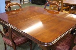 A reproduction Victorian style mahogany extending dining table with two leaves and a set of four
