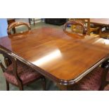 A reproduction Victorian style mahogany extending dining table with two leaves and a set of four