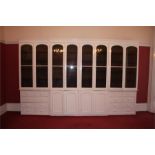 A large painted pine breakfront bookcase with moulded cornice below eight arched and glazed doors