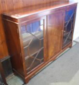 A reproduction mahogany bookcase with plain central door flanked by two glazed doors, supported on