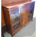 A reproduction mahogany bookcase with plain central door flanked by two glazed doors, supported on