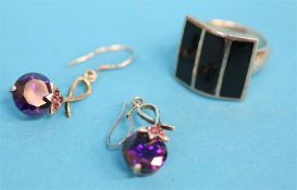 A decorative silver ring and a pair of silver earrings.