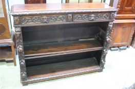 An early 20th century oak carved bookcase with two drawers with carved lion mask handles and two