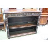 An early 20th century oak carved bookcase with two drawers with carved lion mask handles and two