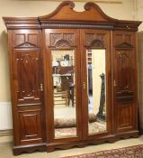 An Edwardian mahogany triple door wardrobe, the top with moulded and swan neck pediment, below three