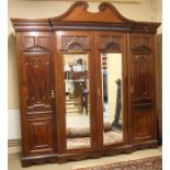 An Edwardian mahogany triple door wardrobe, the top with moulded and swan neck pediment, below three