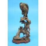 A finely carved Japanese meiji period wood sculpture of a bird of prey seated on a naturalistic