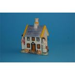 A 19th century pottery money box in the form of a small cottage with a man and woman stood to the