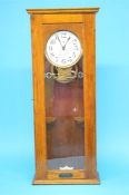 A German oak cased electric wall clock "Elektrische Normaluhr" with enamelled dial.  84 cm high.