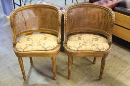 A pair of distressed French style canework and gilt painted oval shaped bedroom chairs.