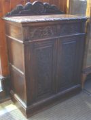 A carved oak side cabinet with raised back below two drawers and two cupboard doors, supported on