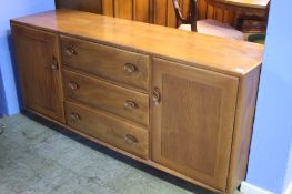 An Ercol Golden Dawn dresser base with three central drawers flanked by two cupboard doors.  155