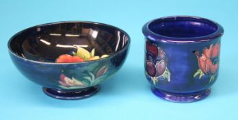 A modern Moorcroft pot decorated with flowers and a shallow circular bowl, both on a dark blue