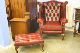 A burgundy Chesterfield wing armchair and foot stool.