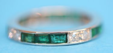 A platinum emerald and diamond eternity ring.