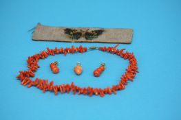 An orange coral necklace, a carved coral pendant, a pair of drop earrings and a beadwork band