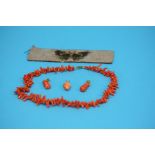 An orange coral necklace, a carved coral pendant, a pair of drop earrings and a beadwork band