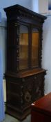 An early 20th century carved oak glazed bookcase with moulded cornice and glazed doors below one