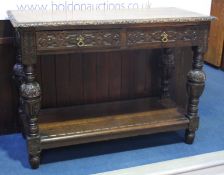 A carved oak two drawer side table with bulbous carved supports.