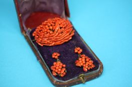An orange coral oval brooch and a pair of orange coral earrings.