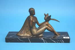 A 1930's Art Deco Spelter figure of a lady seated with a bird balanced on her left hand, supported