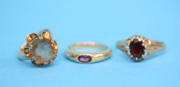 Three 9ct gold rings, one set with a garnet the other with a large citrine and a purple stone set