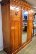A mahogany Rose Brothers wardrobe with central glazed door flanked by two panelled doors,