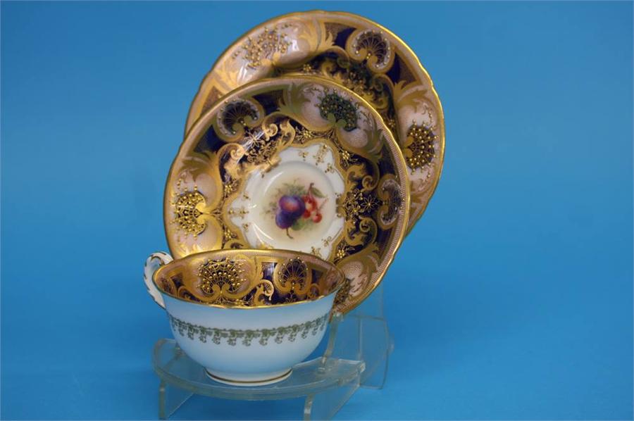 A Royal Worcester trio decorated by Jack Stanley painted with plums, cherries and apples with a