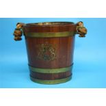 An oak bucket with rope and leather swing handle, brass mounts, the front decorated with a coat of