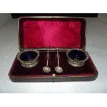 Cased pair of Late Victorian silver salts repoussé decorated with half reed whorled bodies, vacant