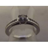 A 9ct White Gold ring set with central Diamond and 18 Diamond to Shoulders, Boxed with C.O.A, Size