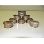 Set of eight contemporary silver 'D' shaped napkin rings, engine turned with vacant cartouches,