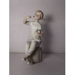 Lladro figure of a seated girl holding a doll, 18cm in height