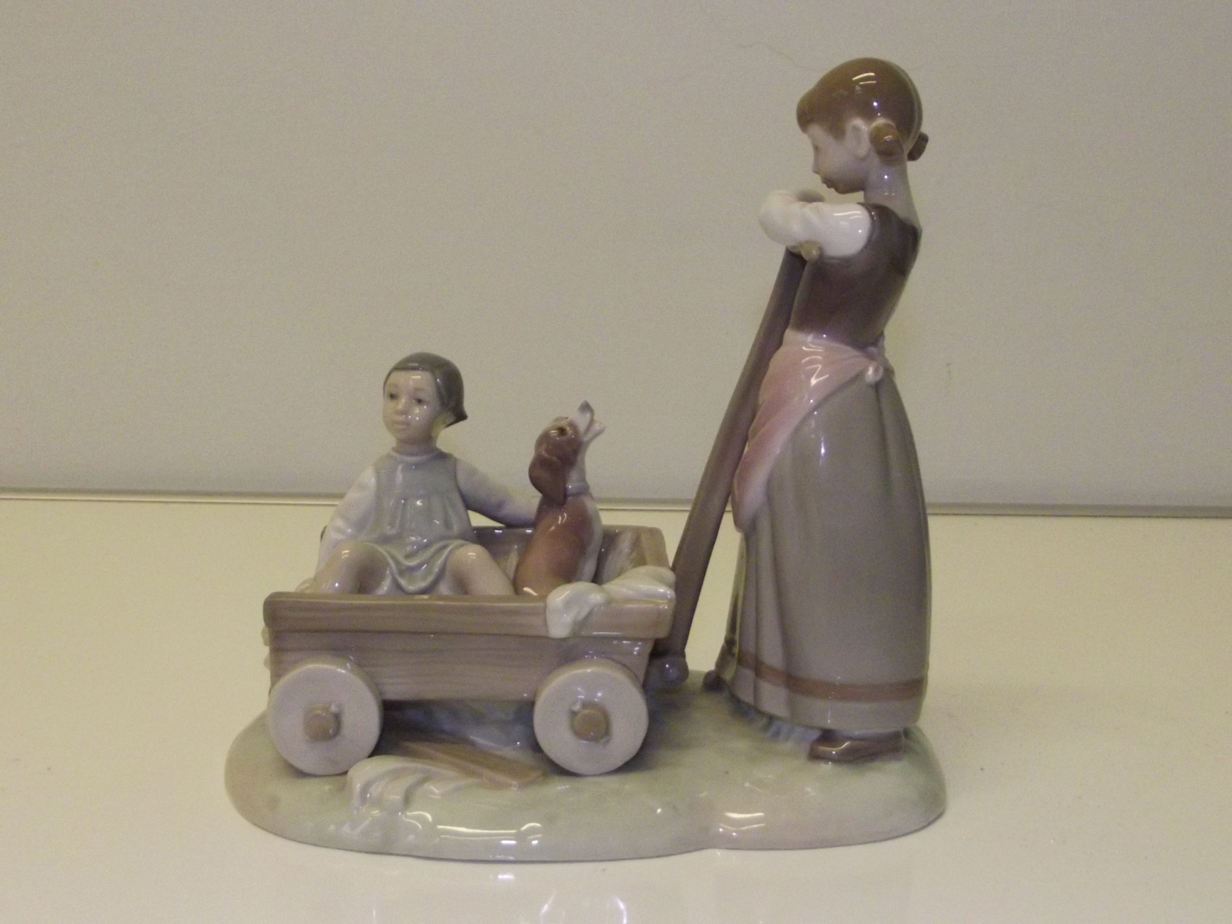 Lladro figure group of girl with a cart containing boy and hound, 21.5cm in height